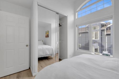 a white bedroom with a large window and a bed at Guest House in Calgary Downtown in Calgary