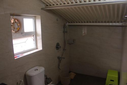 a bathroom with a shower and a toilet and a window at The Attic at Infinity Valley in Kotagiri
