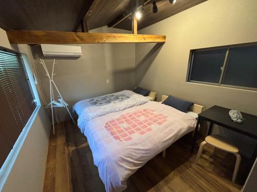 a small bedroom with a bed and a desk at コハクサカイミナト in Sakaiminato