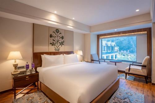 a bedroom with a large bed and a large window at Radisson Hotel Sonamarg in Sonāmarg