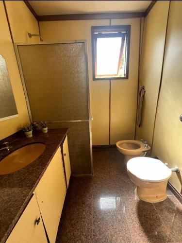 a bathroom with a toilet and a sink and a shower at Casa aconchegante in Teresópolis