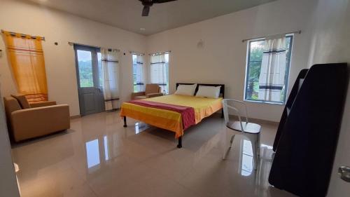 a bedroom with a bed and a couch and windows at Moner Pukur in Bolpur