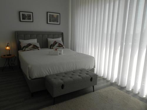 a bedroom with a white bed with a bench next to a window at Bolhão Skyline in Porto