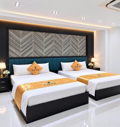 a bedroom with two beds with orange pillows at Love Luxury Hotel Bà Điểm in Ho Chi Minh City
