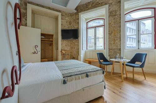 a bedroom with a bed and two chairs and a table at Casa da Portagem by PURUS in Coimbra