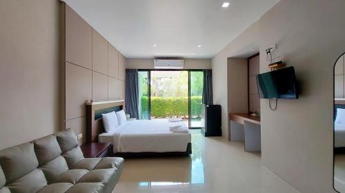 a bedroom with a bed and a couch and a television at LK Resort in Ban Map Khao Wan