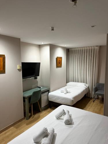 a hotel room with two beds and a flat screen tv at Boutique Hotel Castilla in Soria