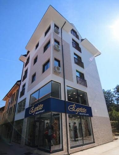 a tall white building with a store front at Egoiste Guesthouse Zlatibor Center in Zlatibor