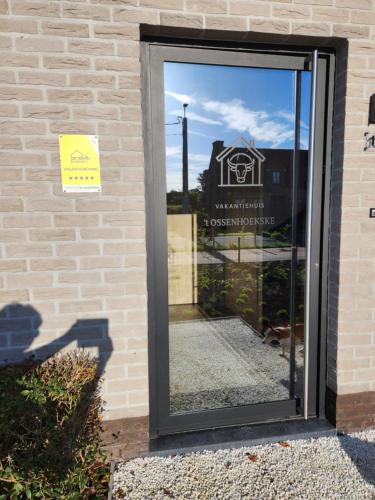 a glass door with a sign on the side of a building at 't Ossenhoekske in Sint-Niklaas