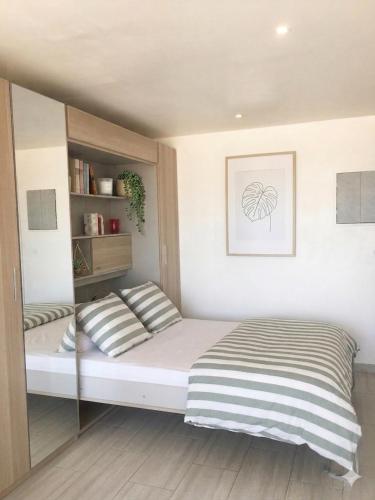 a bed with striped pillows in a bedroom at Studio entre Mer et Lagune in Saint-Aygulf