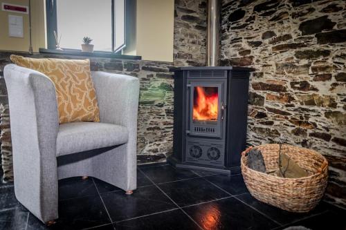a fireplace in a living room with a chair and a stove at Férias na Serra # Natureza # Casa da Professora By ALzira in Seia