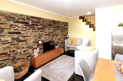 a living room with a stone wall at Férias na Serra # Natureza # Casa da Professora By ALzira in Seia