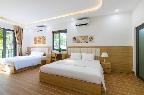two beds in a bedroom with white walls and wood floors at Happy House Villa Phu Quoc in Phú Quốc