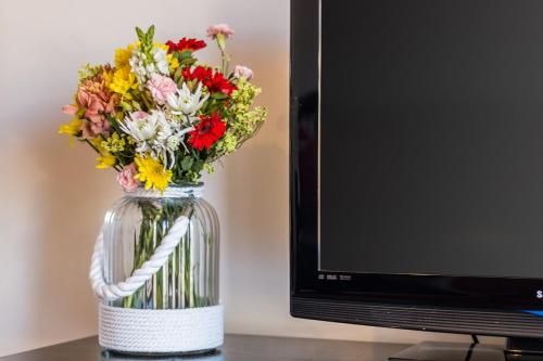 a vase filled with flowers in front of a tv at Vandalou By ALzira in Albufeira