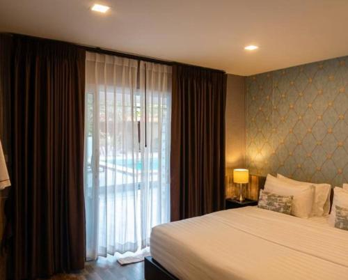 a bedroom with a bed and a large window at All Times Pool Villas in Ban Tha Khun