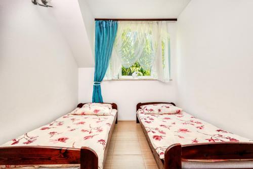 two beds in a small room with a window at Pokoje JANTARUS in Jantar