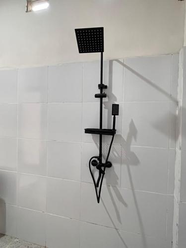 a shower with a black rack on a white wall at KUTA GLORI Homestay in Kuta Lombok