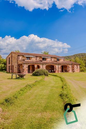 an old brick building in the middle of a field at Hotiday Massa Marittima in Massa Marittima