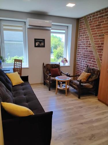 a living room with couches and a brick wall at Apartamentai Heydekrug in Šilutė