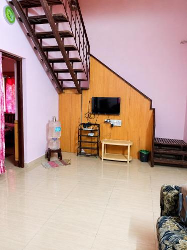 a living room with a tv on a wall at Comfort Cottage in Yercaud