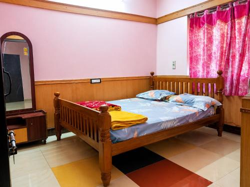 a bedroom with a wooden bed and a television at Comfort Cottage in Yercaud