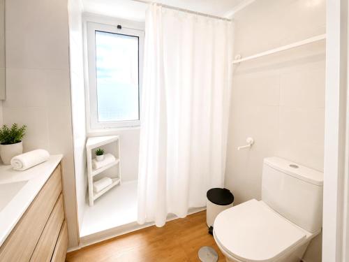 a white bathroom with a toilet and a window at Ocean House Costa del Sol apartamentos varios by Costa del Sol Stay in Torremolinos