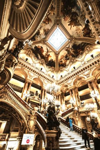 a large building with a staircase and a ceiling at Hotel Riviera OPERA Cadet in Paris