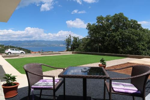 a table and chairs on a patio with a lawn at Apartmani Marin1 in Vrbnik