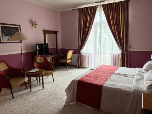 a hotel room with a bed and a desk and a window at Angelo Doro Hotel in Ploieşti