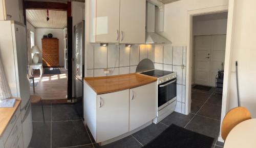 a kitchen with white cabinets and a wooden counter top at Søgården, 3080 Tikøb in Tikøb