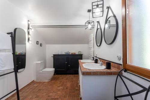 a bathroom with two sinks and a toilet and mirrors at Domaine Cherps Spa - Quietude in Vielleségure
