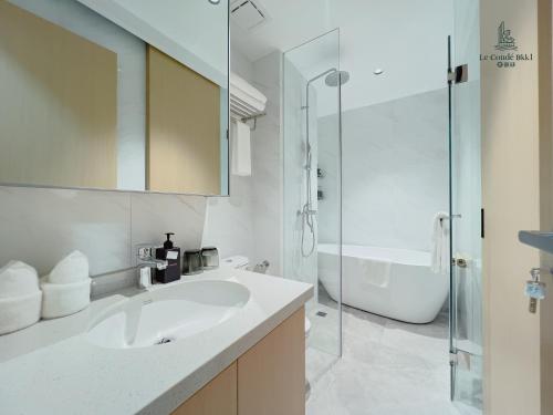 a white bathroom with a sink and a shower at Le Conde Maison in Phnom Penh