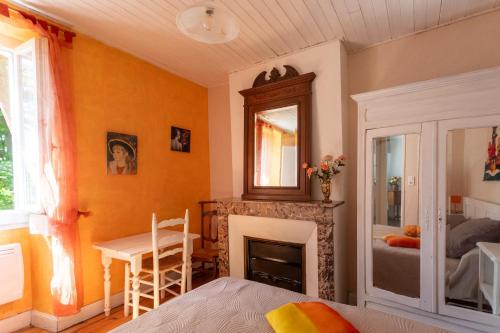 a bedroom with a fireplace and a table and a bed at L'Authentique Maison Béarnaise in Lagor