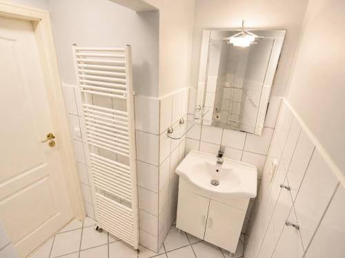a white bathroom with a sink and a mirror at Bauernhaus 3 -Vaest- in Fehmarn