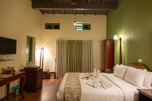 a bedroom with a large bed with white sheets at Springdale Heritage in Thekkady