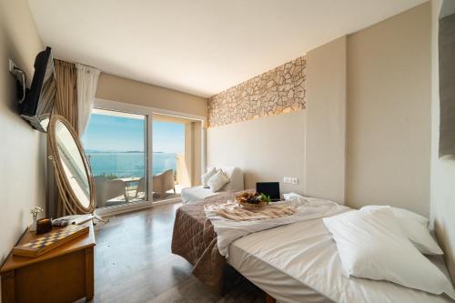 a hotel room with a bed and a large window at Aeolos Bay Tinos in Tinos