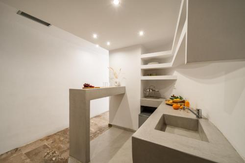 a white kitchen with a sink and a counter at Aeolos Bay Tinos in Tinos