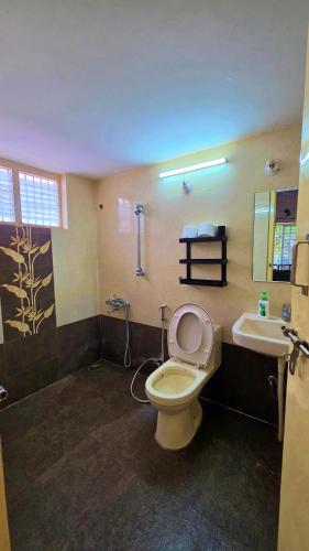 a bathroom with a toilet and a sink and a tub at Manasthala Brindavan in Mysore