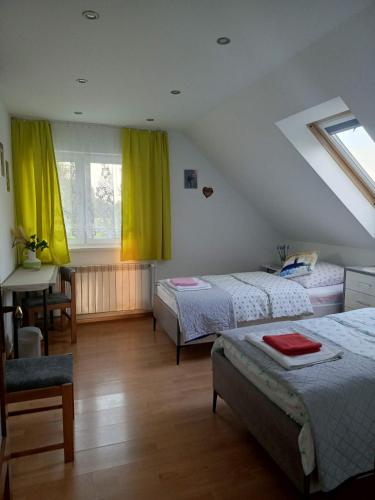 a bedroom with two beds and a table and a window at Dom w Chomranicach- Jacuzzi, domek grillowy in Chomranice