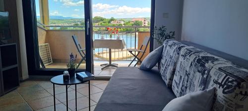 a couch in a living room with a view of a balcony at Apartment Mali Mol in Vantačići