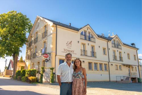 Ein Mann und eine Frau stehen vor einem Gebäude in der Unterkunft Hotel Tommy Wellness & Spa in Náchod