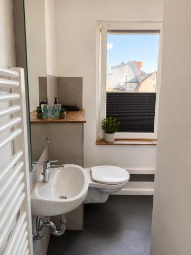 a bathroom with a sink and a toilet and a window at Stilvolles Altbau-Apartment in zentraler Lage mit Workspace in Schwerin