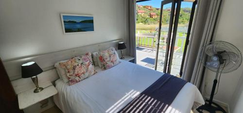 a bedroom with a bed with a fan and a window at Salt River Lodge in Knysna