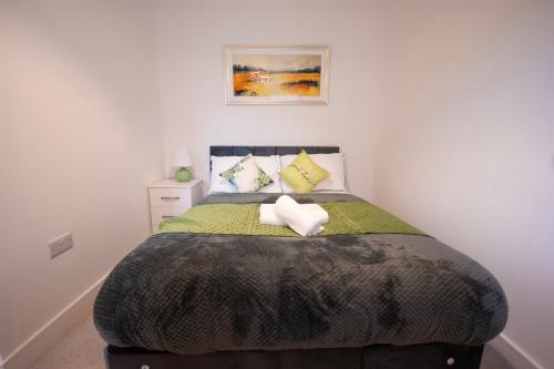 a bedroom with a bed with a green comforter at Derby Luxury Apartments - Curzon in Derby