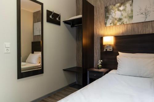a bedroom with a white bed and a mirror at Sørmarka Konferansehotell in Siggerud