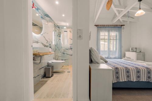 a white bedroom with a bed and a bathroom at Hotel Selini in Agios Nikitas