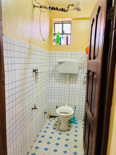 a bathroom with a toilet in a tiled room at Fewa studio in Busia