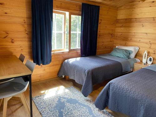a bedroom with two beds in a wooden cabin at Nameliai TRES in Bernotiškė