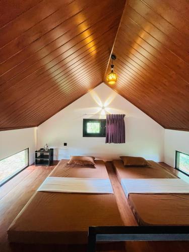 a bedroom with two beds and a wooden ceiling at Knuckles Breeze Villas Kandy in Kandy