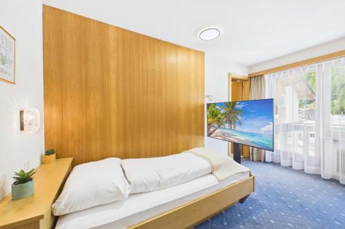 a bedroom with a large flat screen tv on a wooden wall at Cozy single suite with mountain view in Saas-Almagell